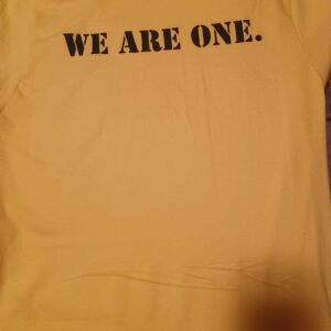 A yellow shirt with the words we are one on it.