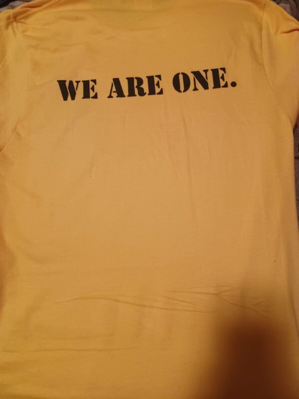 A yellow shirt with the words we are one on it.