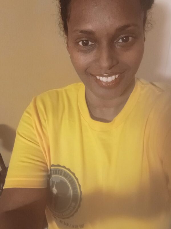 A woman in yellow shirt smiling for the camera.