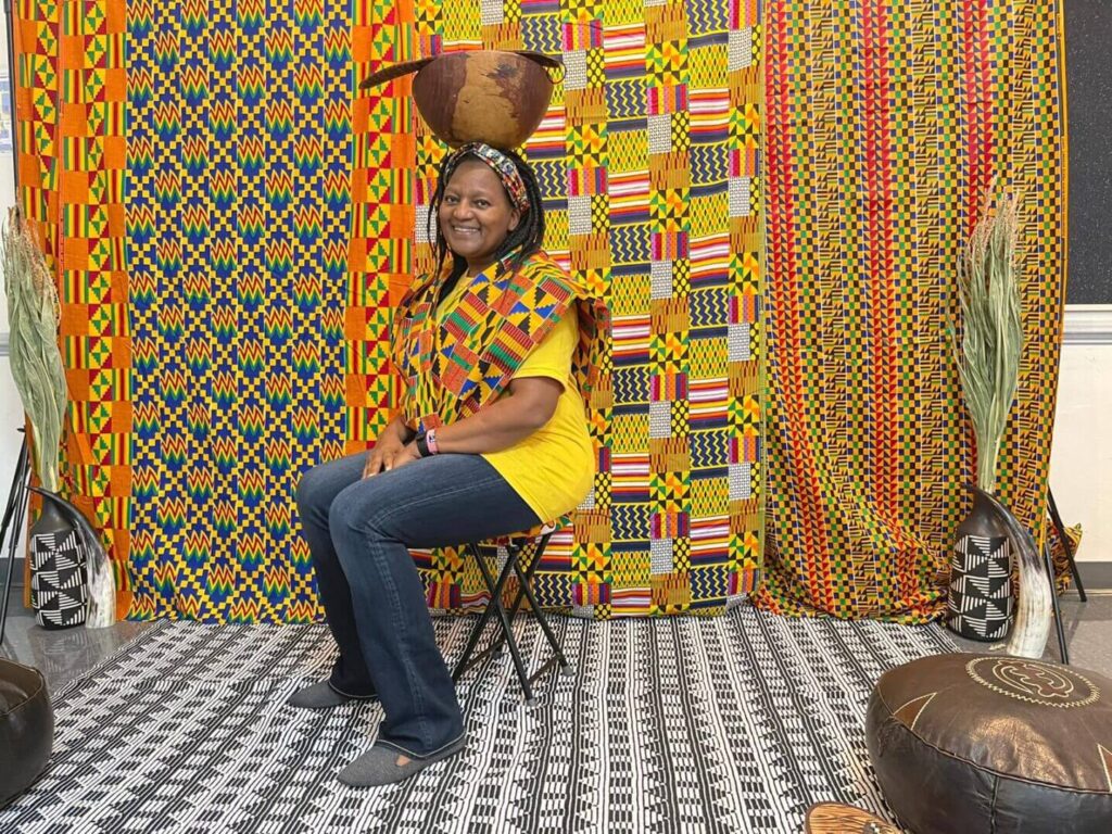 A woman sitting in a chair wearing an african print shirt.