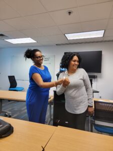 Two women in a room with one holding something.