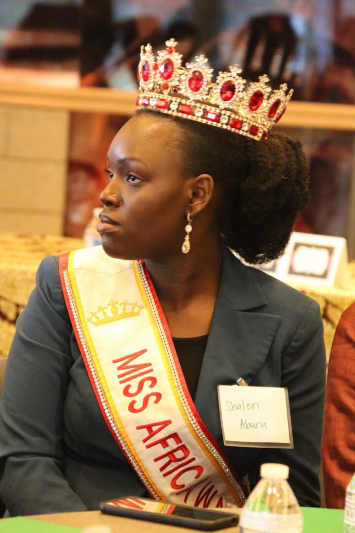 A woman in a crown sitting down.